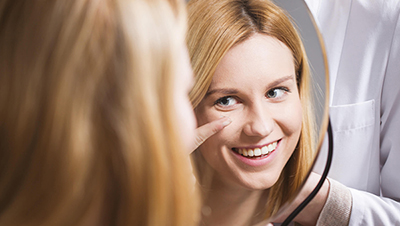 Person smiling and looking into a mirror to apply a contact lens
