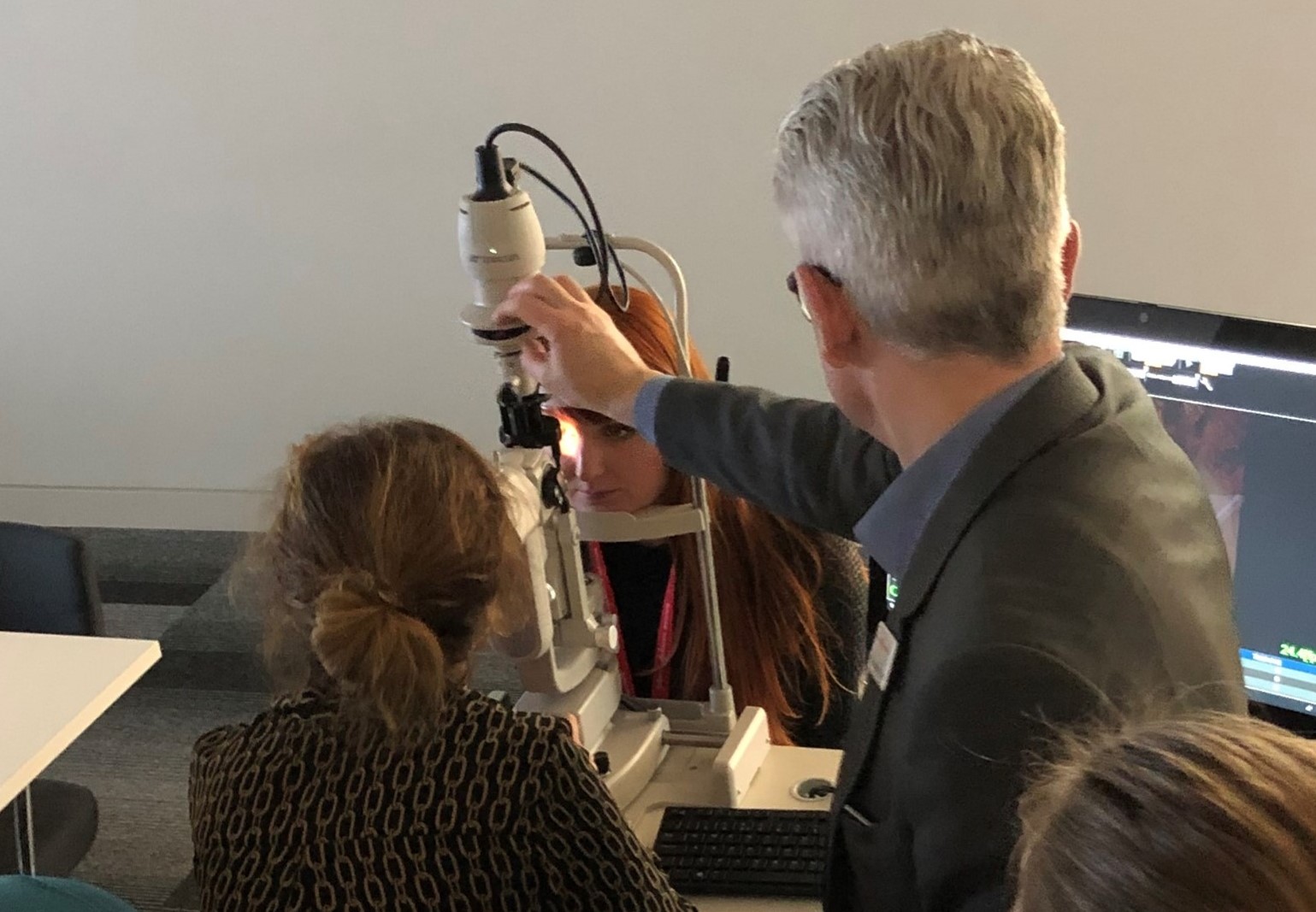 Lecturer teaching students using a slit lamp